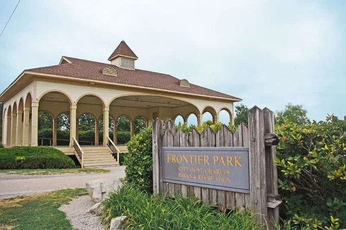 Photo of a pavilion at Frontier Park, with the Park sign in the foreground. It reads: Frontier Park; City of St. Charles; Parks & Recreation. Frontier Park is only a mile away from Vine Street Vacations' Short-Term Rental Properties.