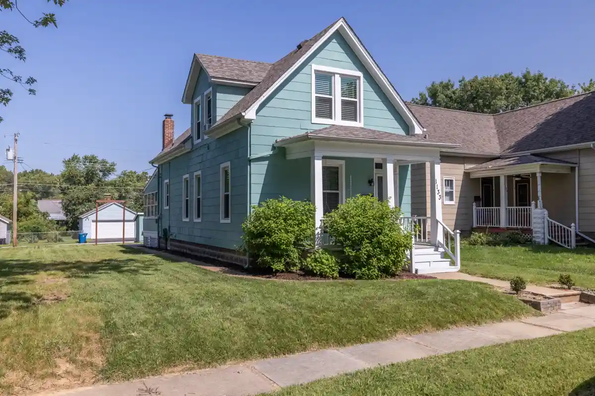 The exterior of the vine street saint charles vacation rental is teal in color and is a shotgun-style home.